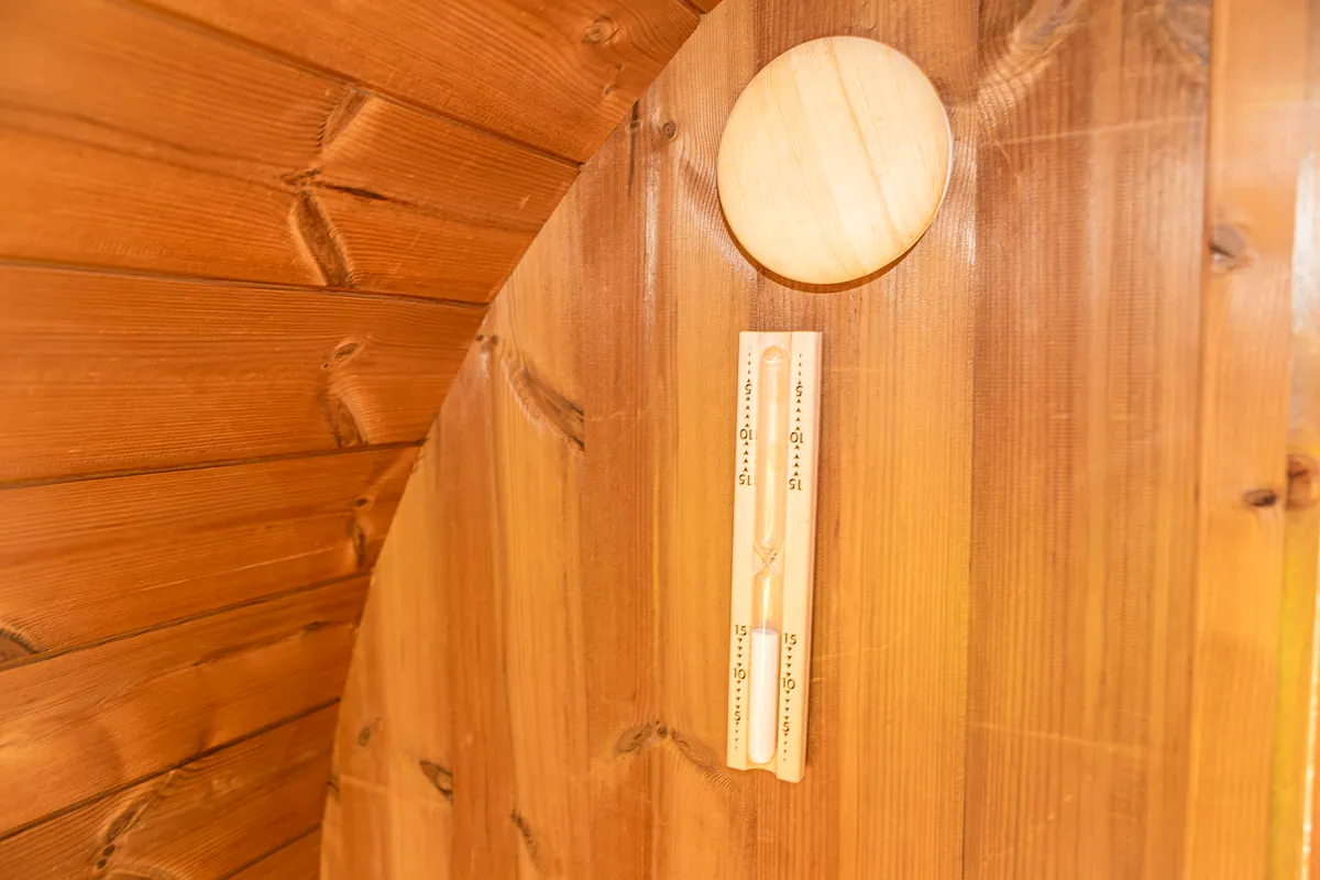 Eine Sanduhr an der gewölbten Holzwand der Sauna.